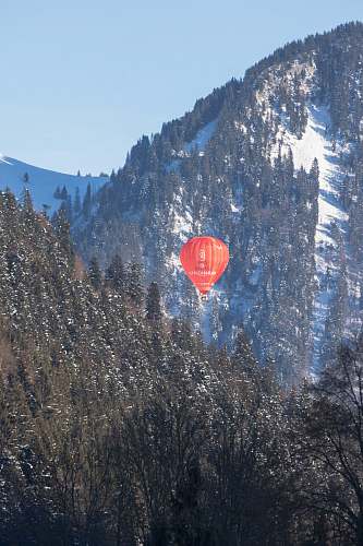 hot air balloon red air balloon between green mountains with trees ball